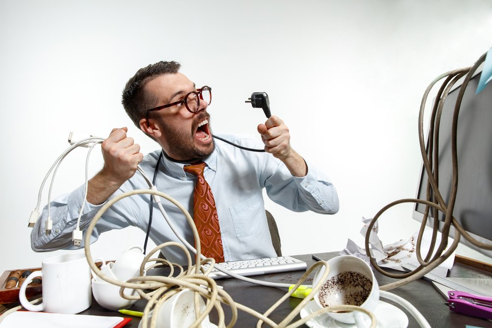 angry man tangling wires at workplace